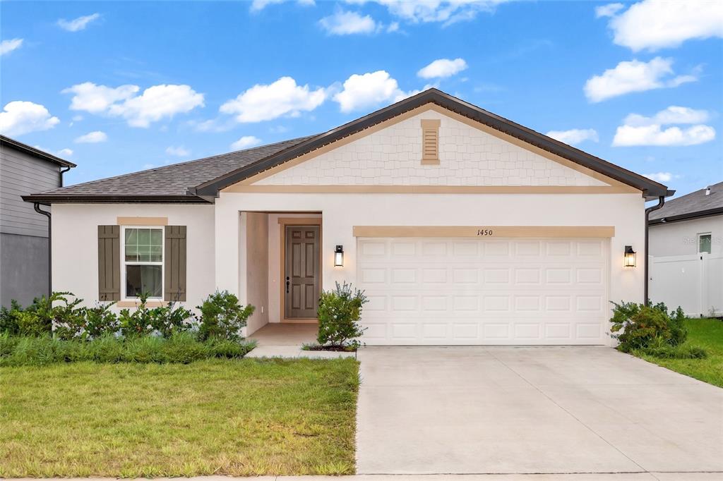 A single-story house with a white stucco facade, a two-car garage, and a front lawn — 1450 ARBOR HILL DRIVE, DELTONA, FL