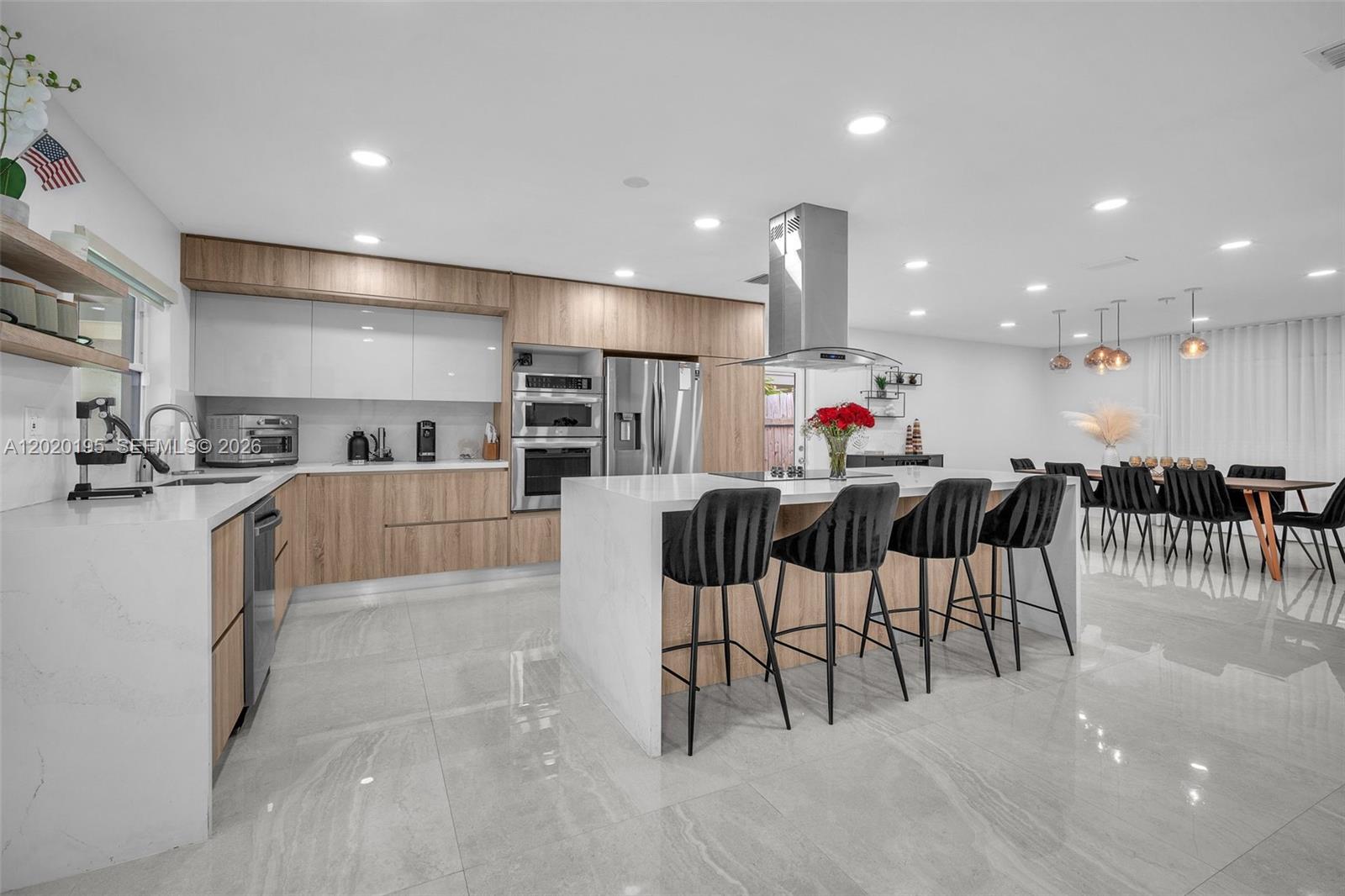 A modern kitchen features light wood cabinetry, white countertops, a large island, and tile flooring — 136 Greens Rd, Hollywood FL 33021, HOLLYWOOD, FL