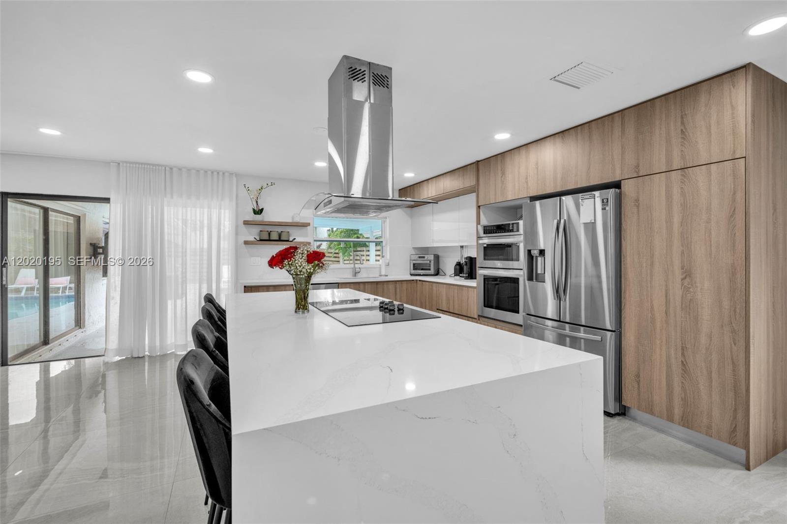 A modern kitchen features a large white quartz island, stainless steel appliances, and wood cabinetry — 136 Greens Rd, Hollywood FL 33021, HOLLYWOOD, FL