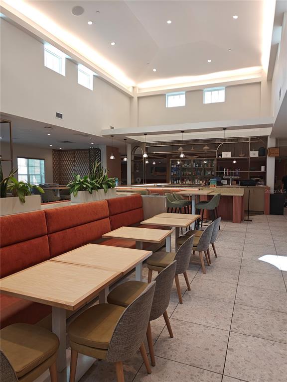 A modern restaurant interior features orange banquette seating, light wood tables, and a bar area — 3151 SUNSET WALK DRIVE UNIT 511, KISSIMMEE, FL