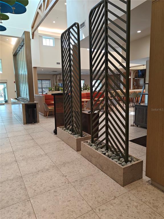 A modern lobby features two tall, chevron-patterned metal room dividers set in stone planters — 3151 SUNSET WALK DRIVE UNIT 511, KISSIMMEE, FL