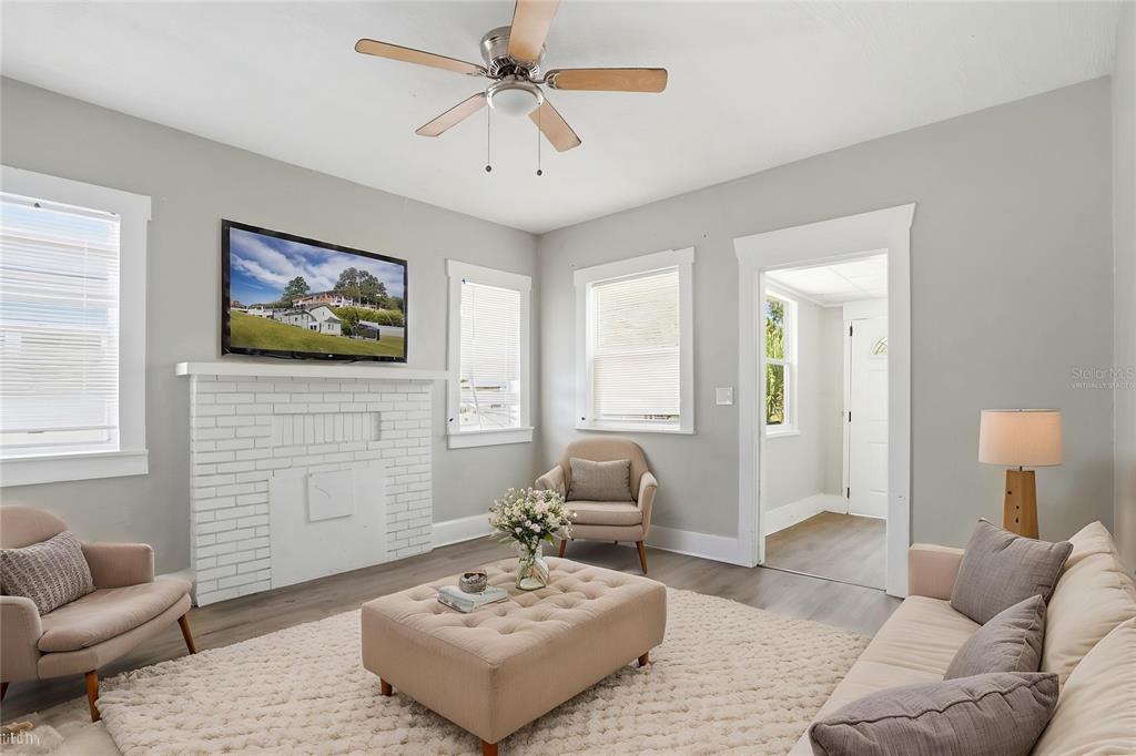 A living room features a white brick fireplace, a television, and neutral-toned furniture — 1909 19TH STREET S, ST PETERSBURG, FL