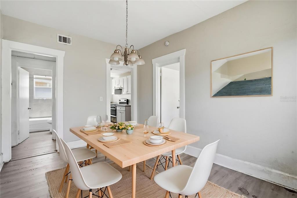 A dining room features a light wood table, white chairs, and a central chandelier — 1909 19TH STREET S, ST PETERSBURG, FL