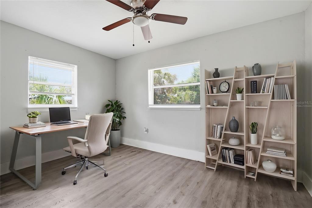 A home office features light gray walls, wood-look flooring, a desk, and a large bookshelf — 1909 19TH STREET S, ST PETERSBURG, FL