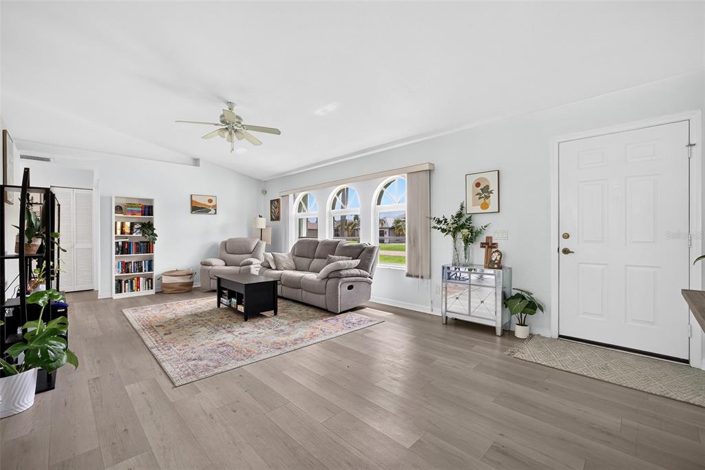 A living room with light wood floors, a grey sofa, and three arched windows — 167 ALLWORTHY STREET, PORT CHARLOTTE, FL