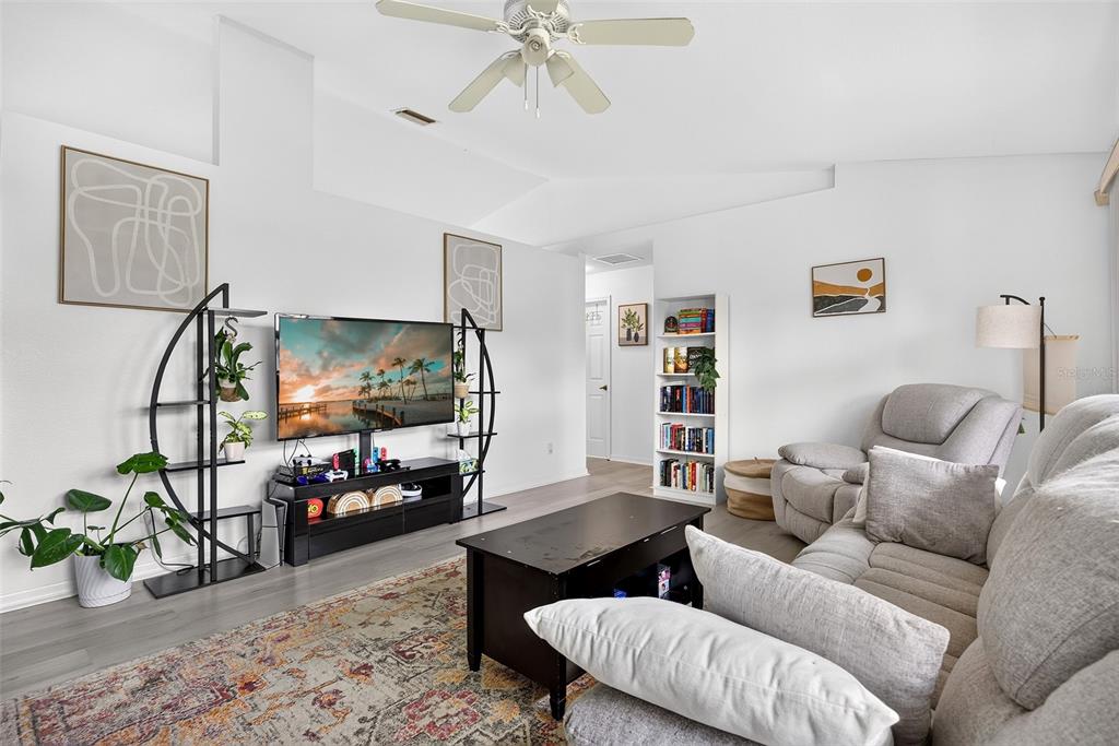 A living room features a television, a grey sofa, a coffee table, and a ceiling fan — 167 ALLWORTHY STREET, PORT CHARLOTTE, FL