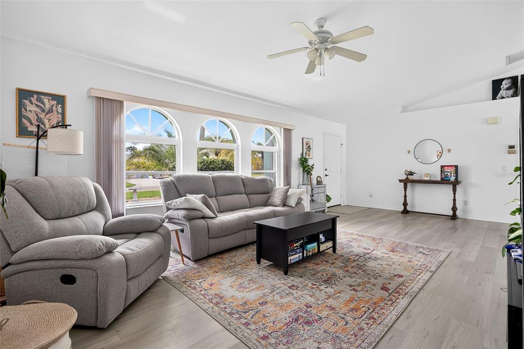 A living room features gray furniture, a patterned area rug, and three arched windows — 167 ALLWORTHY STREET, PORT CHARLOTTE, FL