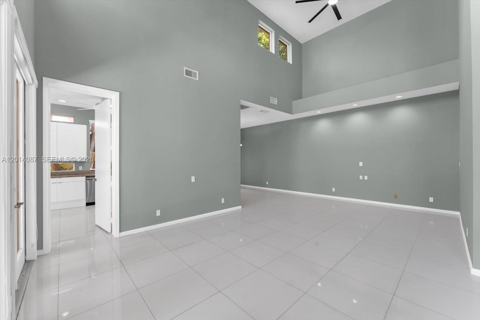 A spacious living room features high ceilings, gray walls, and light-colored tile flooring — 3728 NE 208th Ter, Aventura FL 33180, AVENTURA, FL