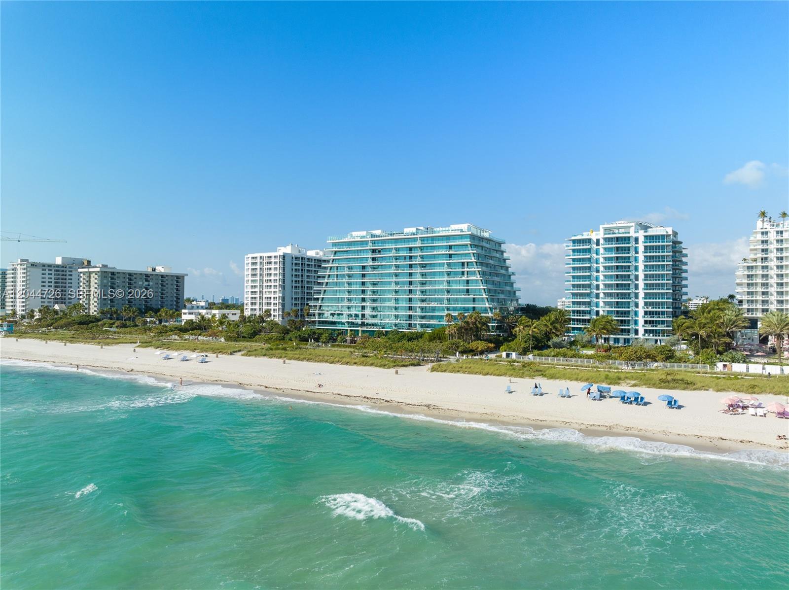 An aerial view shows several high-rise residential buildings situated along a sandy beach — 9349 Collins Ave # 605, Surfside FL 33154, SURFSIDE, FL
