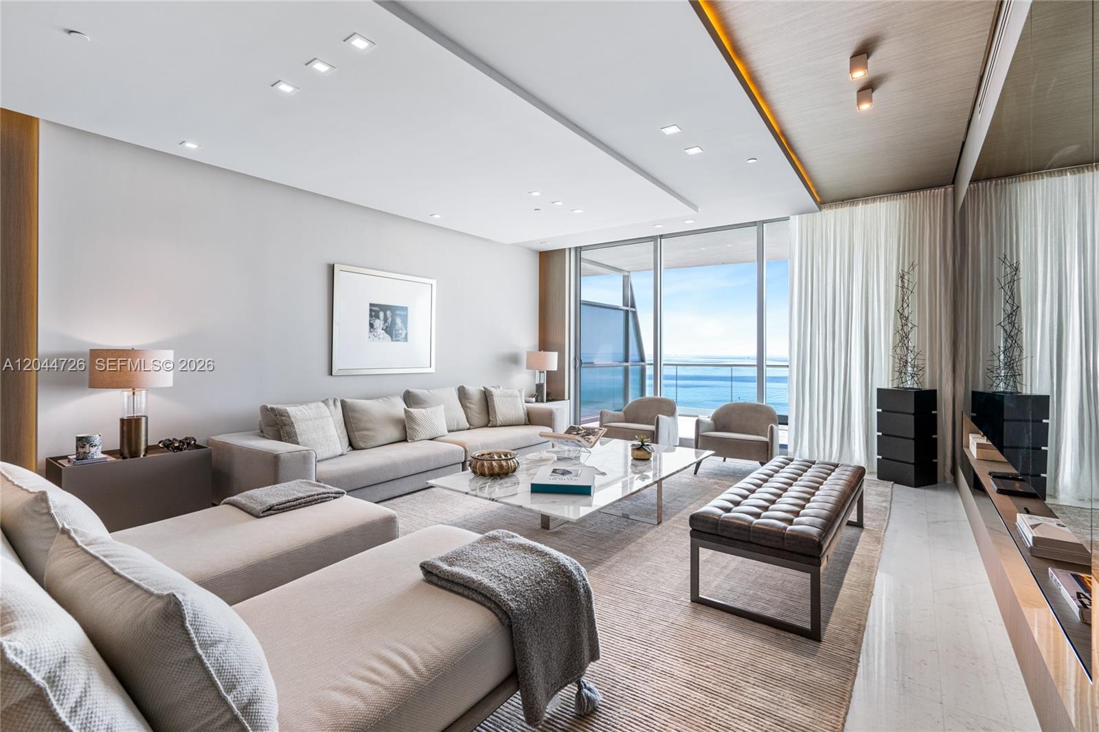 A modern living room features a large sectional sofa, marble coffee table, and ocean views — 9349 Collins Ave # 605, Surfside FL 33154, SURFSIDE, FL