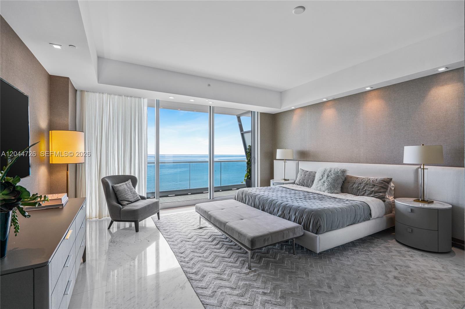 A modern bedroom features a king bed, marble floors, and floor-to-ceiling windows overlooking the ocean — 9349 Collins Ave # 605, Surfside FL 33154, SURFSIDE, FL