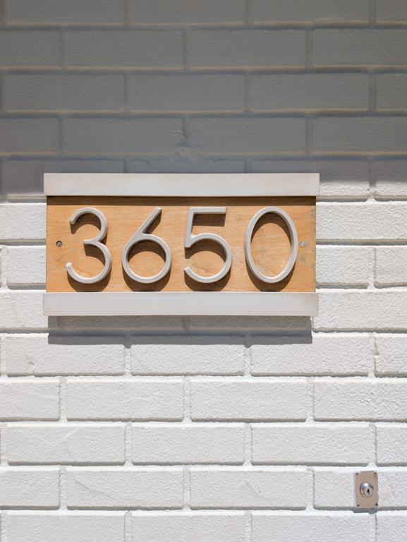 A house number sign with silver digits mounted on a wooden plaque against white brick — 3650 KINGSBURY DRIVE, HOLIDAY, FL