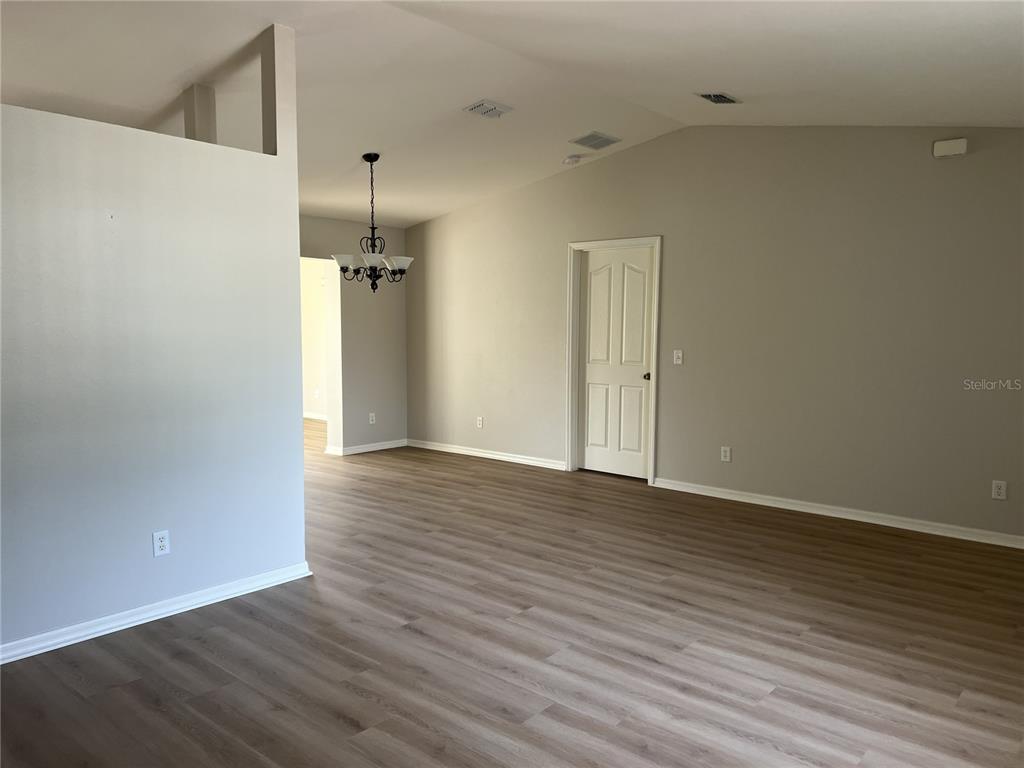 An interior view shows a living area with light wood-look flooring and a dining chandelier — 6035 SW 98TH STREET ROAD, OCALA, FL
