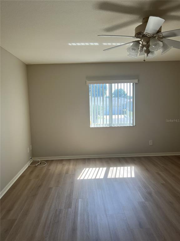An empty room features light-colored wood-look flooring, a ceiling fan, and a window with blinds — 6035 SW 98TH STREET ROAD, OCALA, FL
