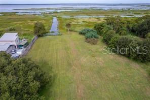 An aerial view shows a grassy lot leading to a waterway with a house nearby — 2930 TOHOPEKALIGA DRIVE, ST CLOUD, FL