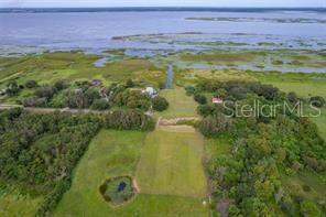 An aerial view shows a grassy lot with a small pond near a large lake — 2930 TOHOPEKALIGA DRIVE, ST CLOUD, FL