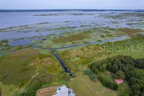 An aerial view shows a house with a pool near a large marshy lake — 2930 TOHOPEKALIGA DRIVE, ST CLOUD, FL