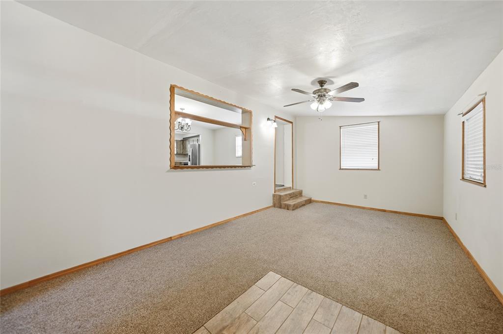 A living room with beige carpet, white walls, a ceiling fan, and a pass-through window — 5549 SW SHORES AVENUE, ARCADIA, FL