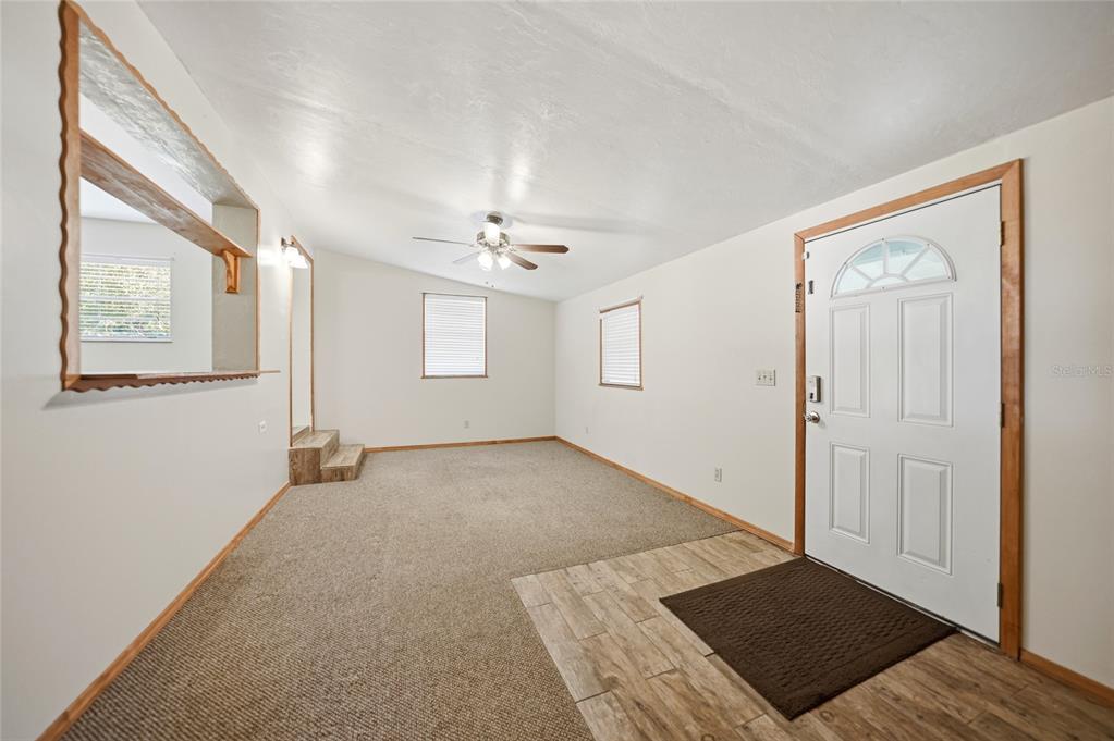 A living room features carpeted flooring, a ceiling fan, and a white front door — 5549 SW SHORES AVENUE, ARCADIA, FL