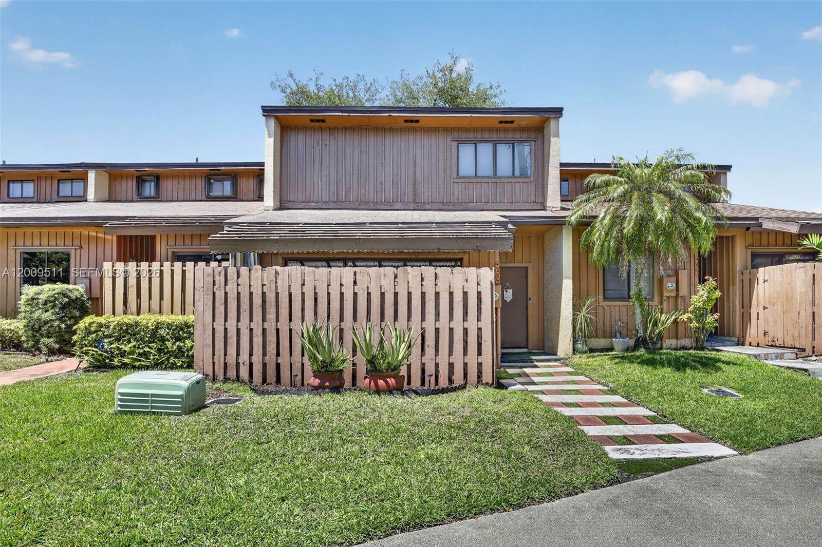 A two-story townhouse exterior features brown wood siding, a fenced patio, and a walkway — 4283 S Pine Island Rd, Davie FL 33328, DAVIE, FL