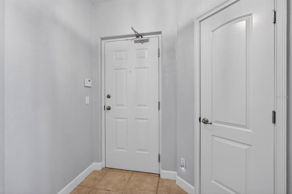 An entryway features a white front door, a closed interior door, and tiled flooring — 424 LUNA BELLA LANE UNIT 330, NEW SMYRNA BEACH, FL