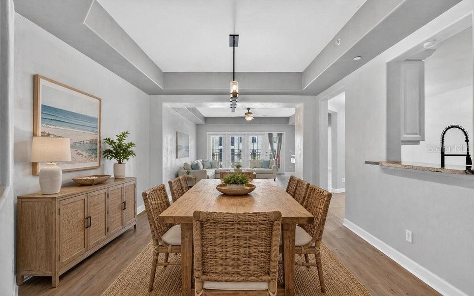 A dining room with a wooden table, wicker chairs, and a sideboard under a tray ceiling — 424 LUNA BELLA LANE UNIT 330, NEW SMYRNA BEACH, FL