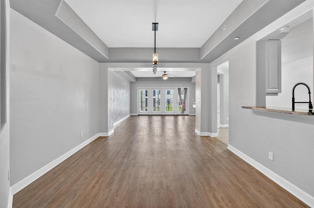 An empty dining area with wood-look flooring, a tray ceiling, and a view of glass doors — 424 LUNA BELLA LANE UNIT 330, NEW SMYRNA BEACH, FL