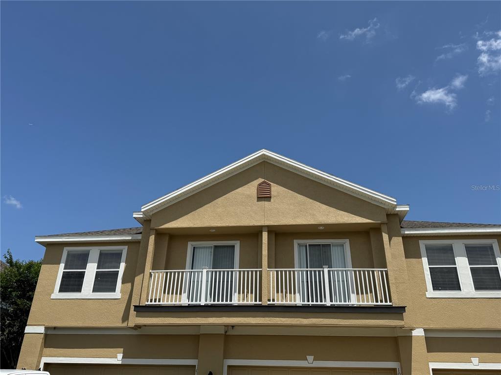 The exterior of a two-story tan building features a balcony with white railings — 10387 WINDING MARSH TRAIL UNIT 2, ORLANDO, FL