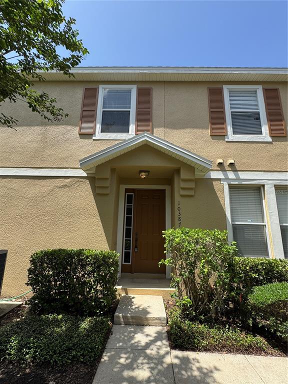A two-story tan stucco townhouse features a brown front door under a small gable roof — 10387 WINDING MARSH TRAIL UNIT 2, ORLANDO, FL