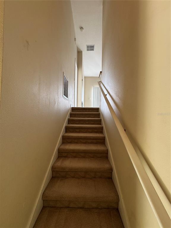 A carpeted staircase with a white handrail leads to an upper landing — 10387 WINDING MARSH TRAIL UNIT 2, ORLANDO, FL