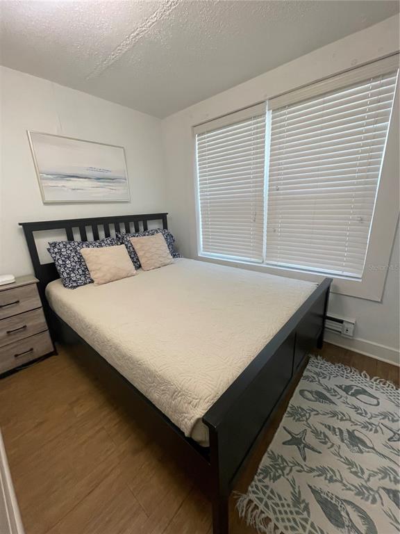 A bedroom features a black bed frame, light-colored bedding, a dresser, and a window with blinds — 2513 8TH AVENUE W, BRADENTON, FL