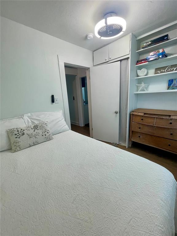A bedroom features a white bed, a wooden dresser, built-in shelving, and a doorway — 2513 8TH AVENUE W, BRADENTON, FL