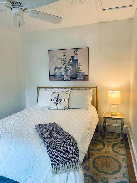 A bedroom features a bed with a white textured quilt, patterned pillows, and a side table — 2513 8TH AVENUE W, BRADENTON, FL