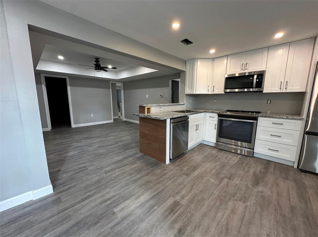 A kitchen with white cabinets, stainless steel appliances, and gray wood-look flooring — 2301 TRELAIN DRIVE S, ST PETERSBURG, FL