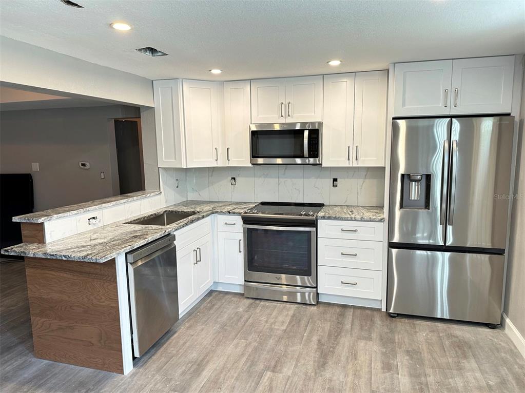 A kitchen features white cabinets, stainless steel appliances, and a marble-patterned countertop — 2301 TRELAIN DRIVE S, ST PETERSBURG, FL