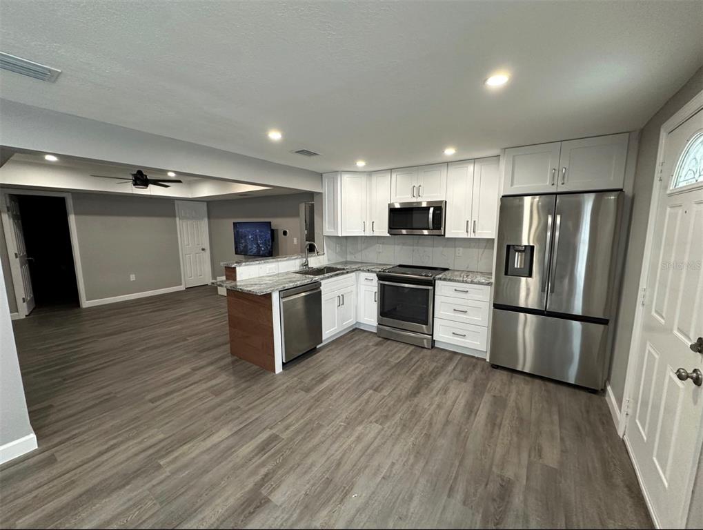 A kitchen with white cabinets, stainless steel appliances, and gray wood-look flooring — 2301 TRELAIN DRIVE S, ST PETERSBURG, FL