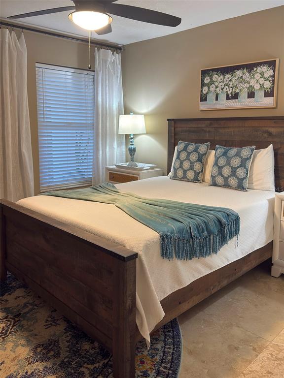 A bedroom features a wooden bed frame, a teal throw blanket, and a floral wall print — 4510 EL CONQUISTADOR PARKWAY UNIT 105, BRADENTON, FL