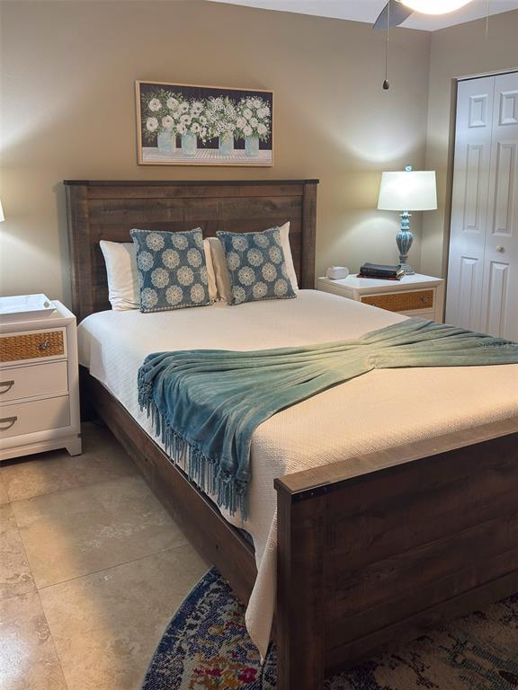 A bedroom features a wooden bed frame, two white nightstands, and a blue patterned throw blanket — 4510 EL CONQUISTADOR PARKWAY UNIT 105, BRADENTON, FL
