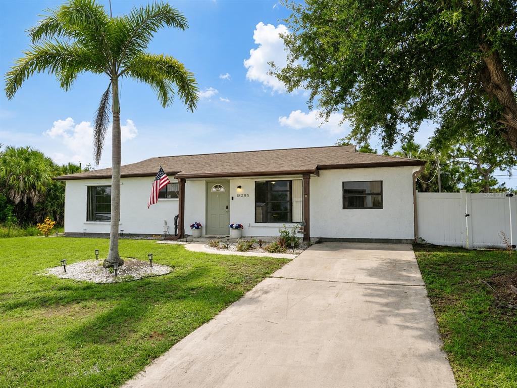 A single-story white house with a palm tree and an American flag by the door — 18295 VAN NUYS CIRCLE, PORT CHARLOTTE, FL