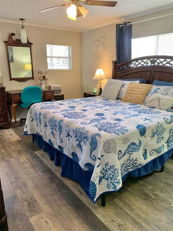 A bedroom features a bed with a coastal-themed quilt, a wooden headboard, and a vanity — 2122 OAK GROVE DRIVE UNIT 79, ZELLWOOD, FL