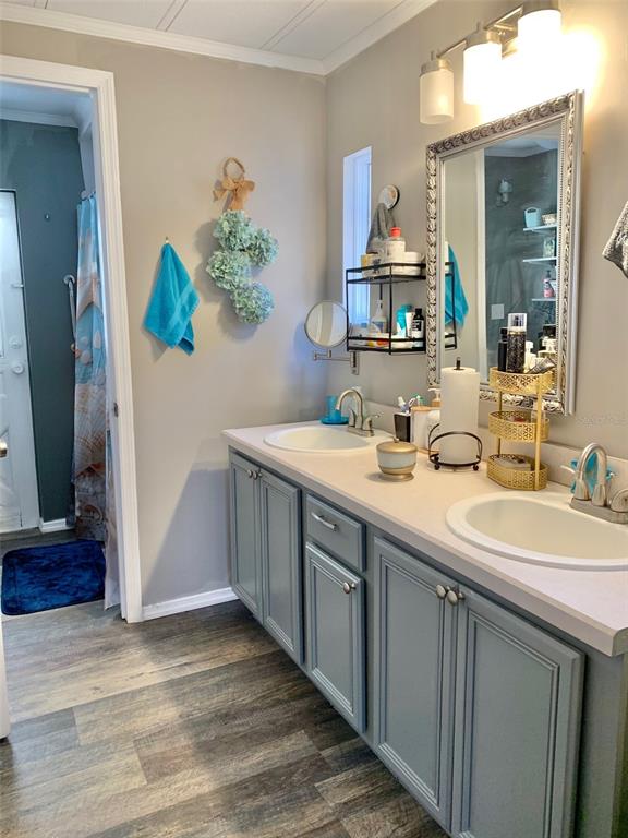 A bathroom features a double-sink vanity with blue cabinets, a silver-framed mirror, and wood-look flooring — 2122 OAK GROVE DRIVE UNIT 79, ZELLWOOD, FL
