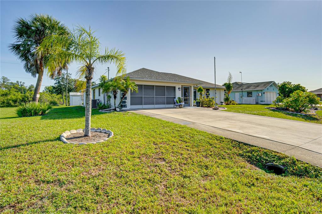 A single-story house with a screened-in garage and a palm tree in the front yard — 12038 FLORENCE AVENUE, PORT CHARLOTTE, FL