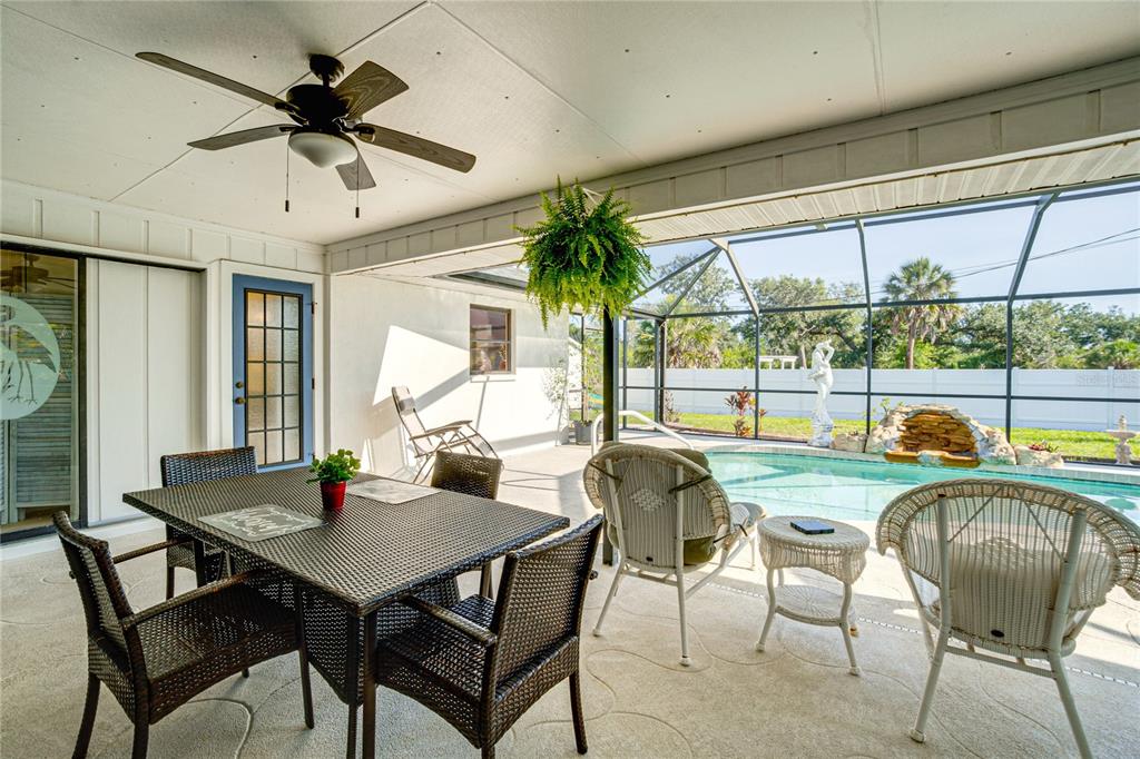 A covered patio features a dining set, wicker chairs, a ceiling fan, and a swimming pool — 12038 FLORENCE AVENUE, PORT CHARLOTTE, FL
