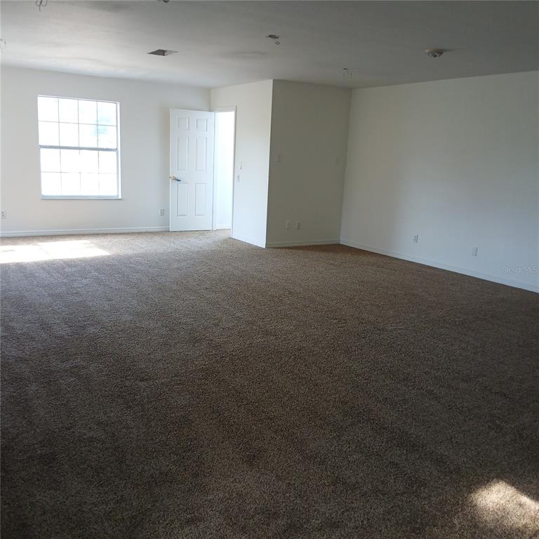 An empty room with beige carpet, white walls, a window, and an open doorway — 2041 N DONOVAN AVENUE 2nd Fl., CRYSTAL RIVER, FL