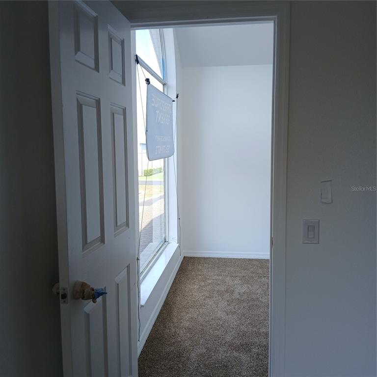 A doorway opens into a small carpeted room featuring a large window with a sign — 2041 N DONOVAN AVENUE 2nd Fl., CRYSTAL RIVER, FL