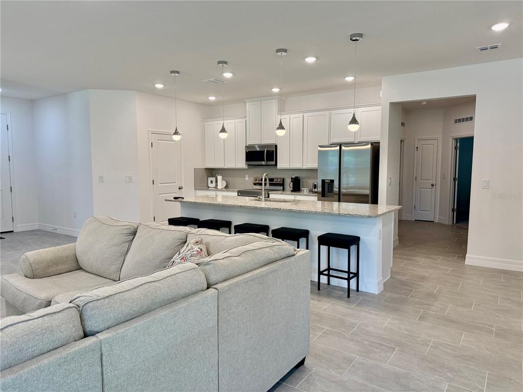 A kitchen with white cabinets and a granite island overlooks a living area — 15467 MAYNARD AVENUE, PORT CHARLOTTE, FL