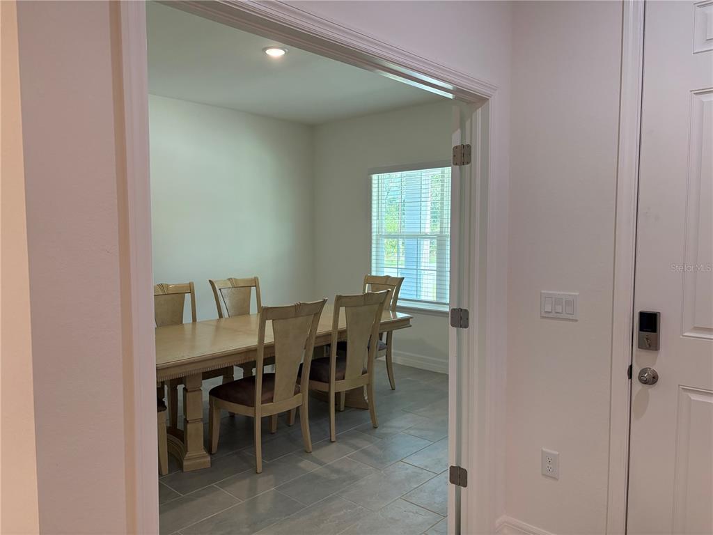 A dining room with a wooden table and chairs is viewed through an open doorway — 15467 MAYNARD AVENUE, PORT CHARLOTTE, FL