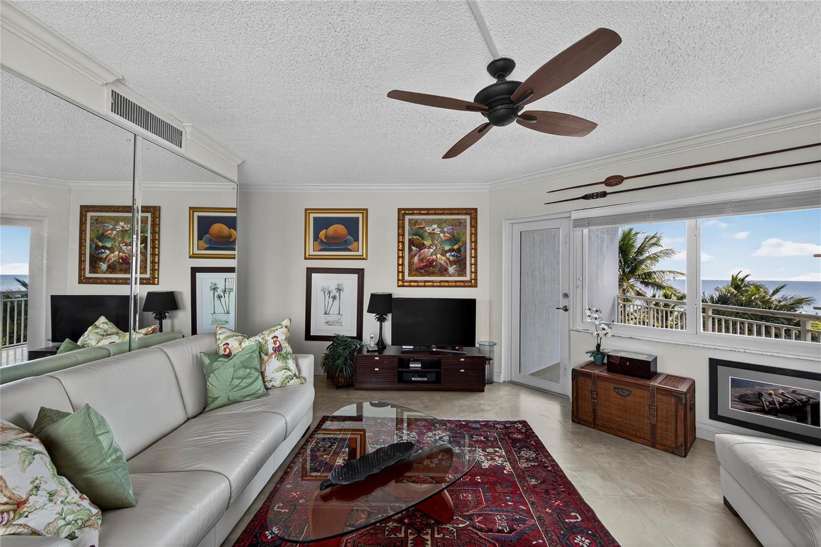 A living room features a white leather sofa, a red patterned rug, and ocean views — 710 N Ocean Boulevard # 312, Pompano Beach FL 33062, POMPANO BEACH, FL