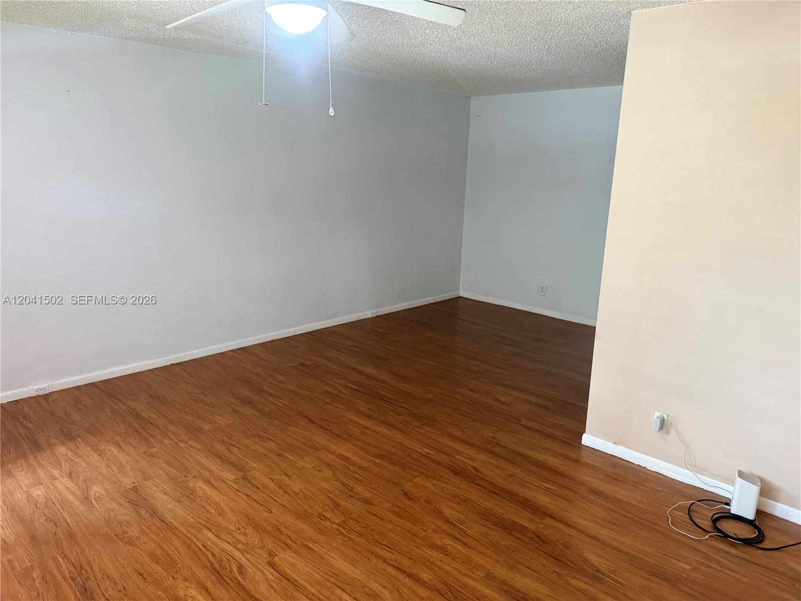 An empty room features light-colored walls, wood-look flooring, and a ceiling fan — PEMBROKE PINES, FL