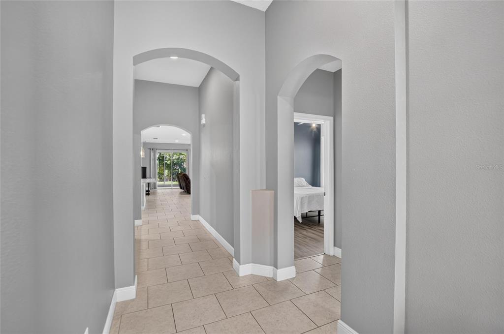 A tiled hallway with arched doorways leads to a living area and a bedroom — 7029 OLD BENTON DRIVE, APOLLO BEACH, FL